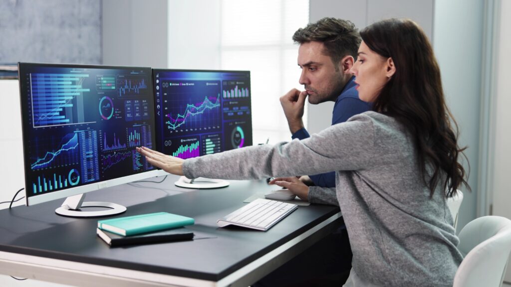 Two people are looking at a computer screen. Tableau vs Power BI Comparison.